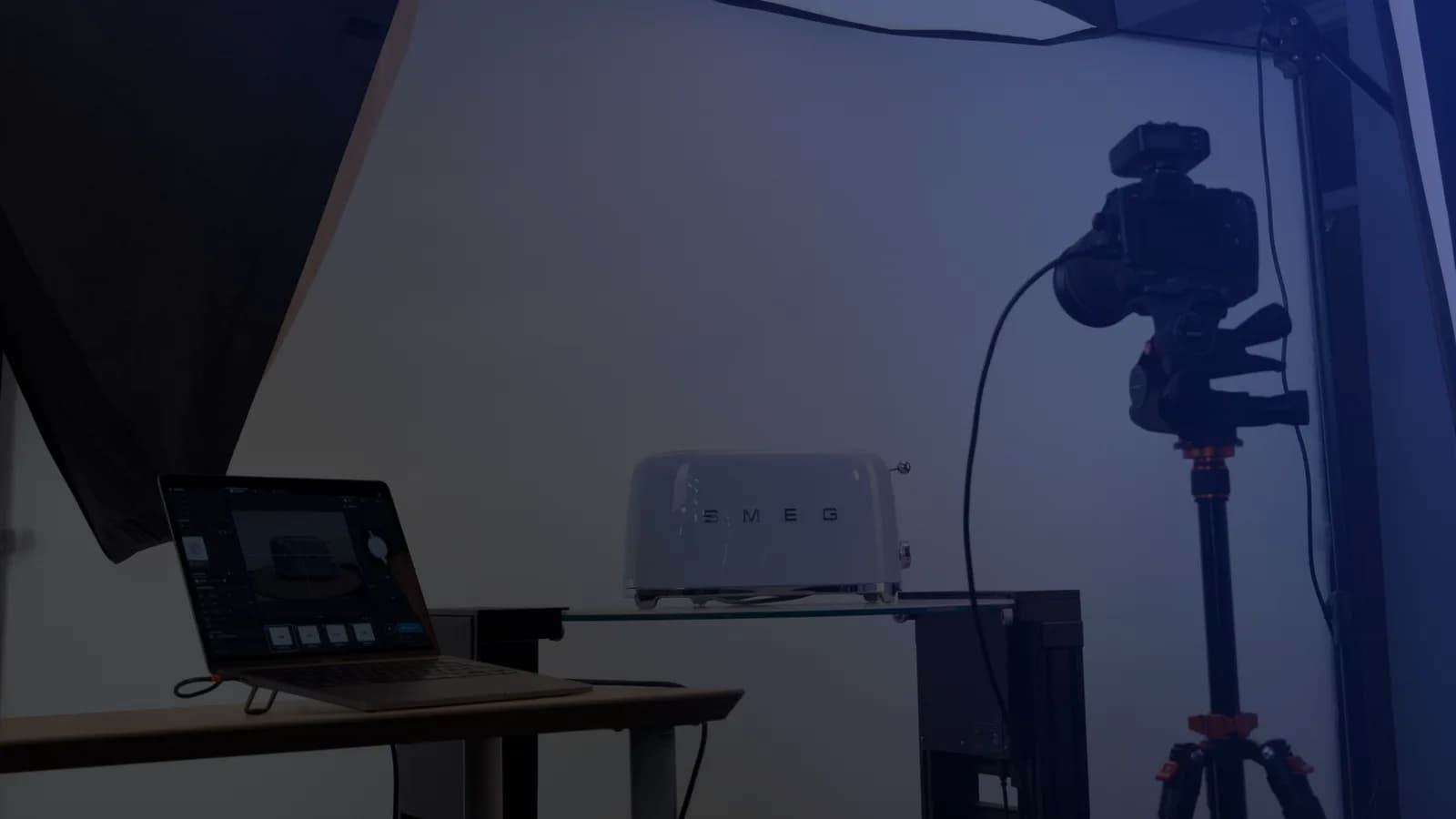 Installation de photographie de produit en tethering : un ordinateur portable avec le logiciel de capture, un appareil photo sur trépied et un produit sur une tablette en verre