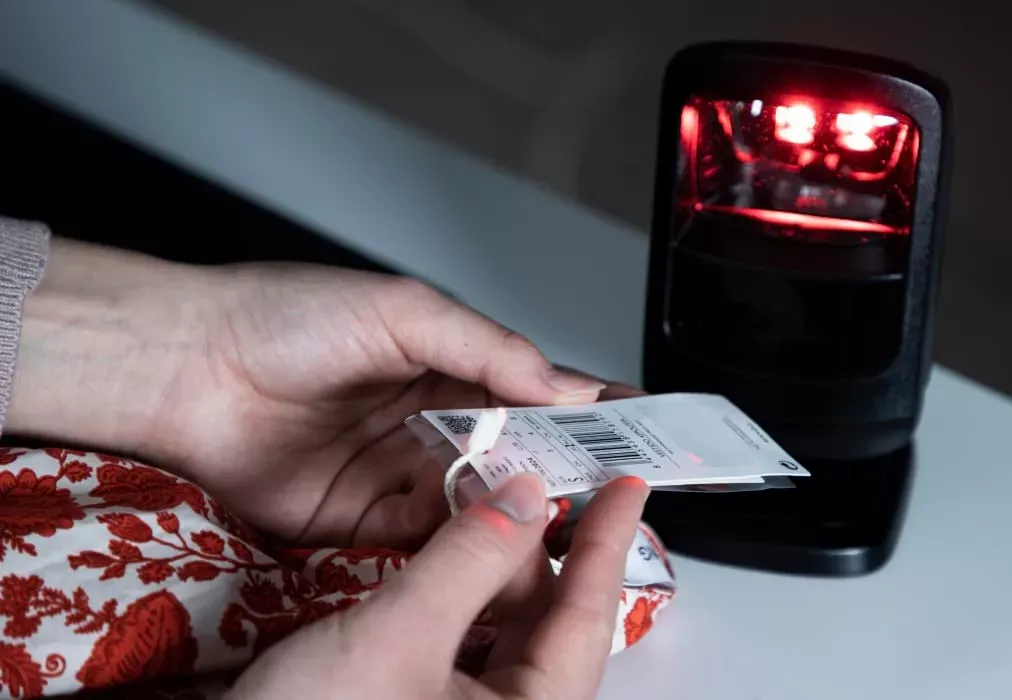Gros plan sur des mains scannant l’étiquette code-barres d’un vêtement pour l’inventaire