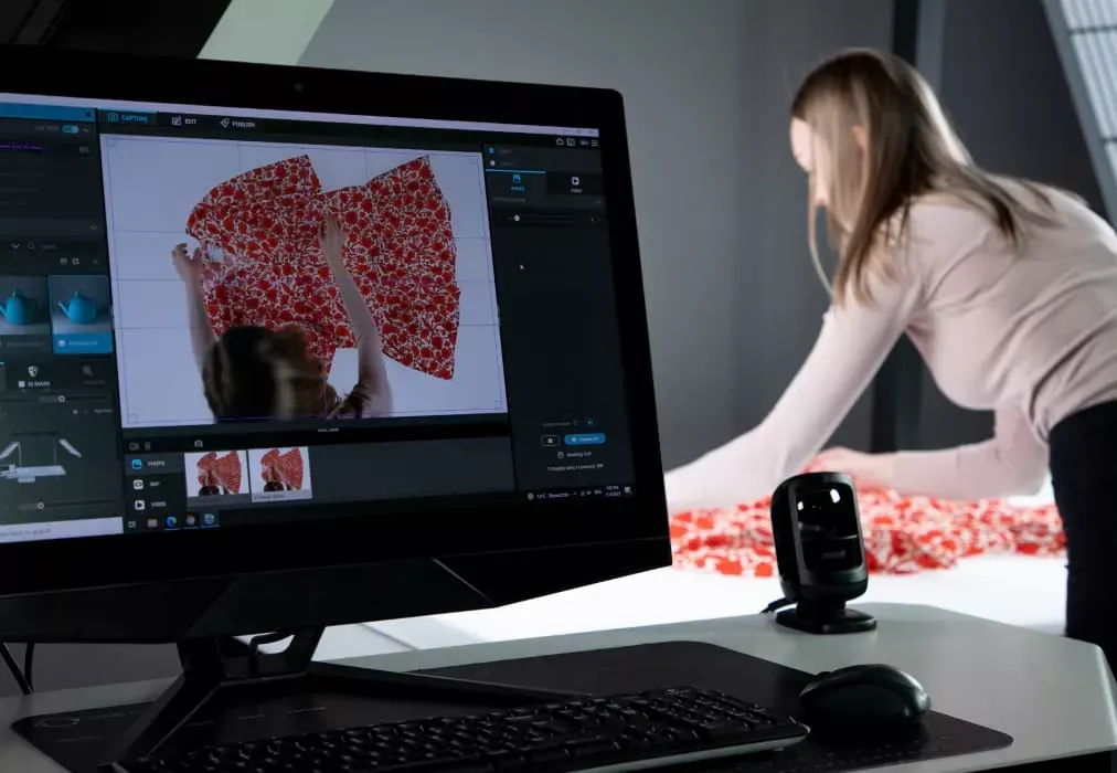 Photographe ajustant un vêtement en tissu fleuri avec aperçu en direct sur le moniteur