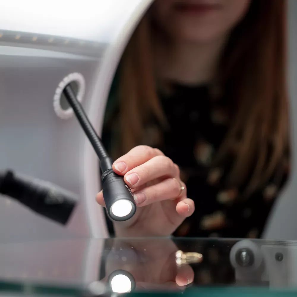 Femme ajustant la lumière LED dans une installation de photographie de bijoux