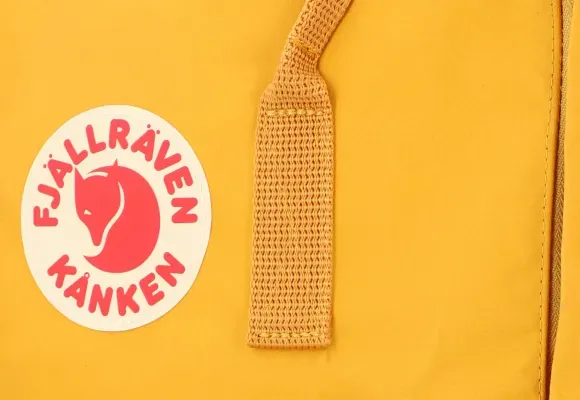 Gros plan du logo et de la sangle du sac à dos Kanken jaune