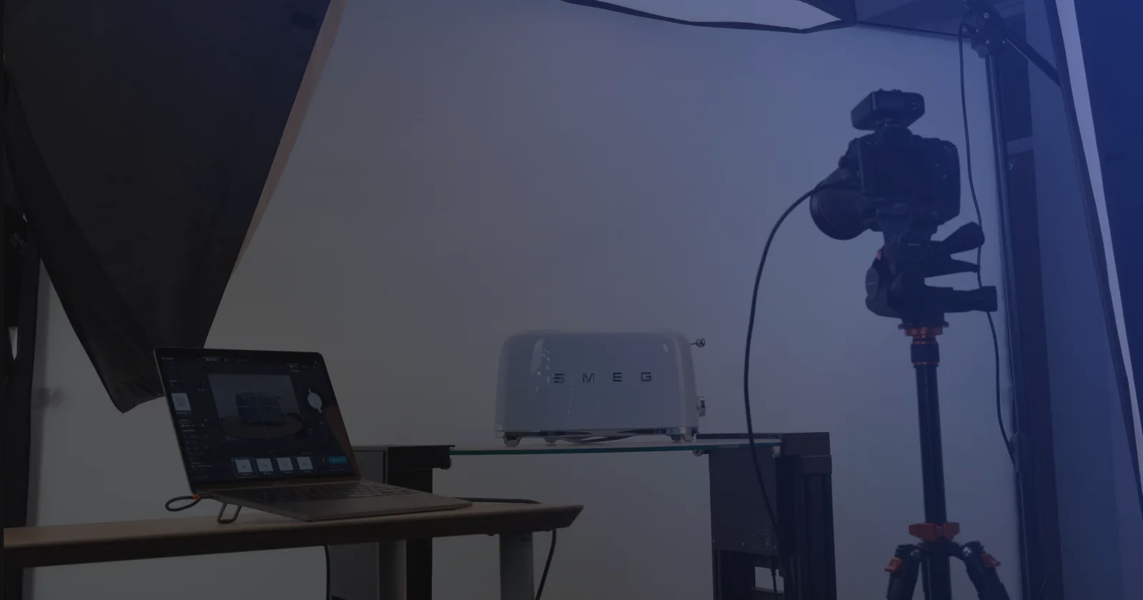 Installation de photographie de produit en tethering : un ordinateur portable avec le logiciel de capture, un appareil photo sur trépied et un produit sur une tablette en verre