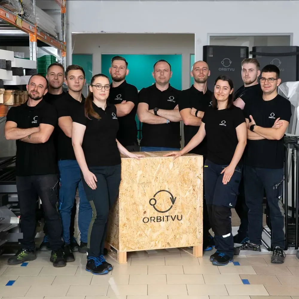 Équipe de production et logistique d’Orbitvu posant avec une caisse en bois de marque