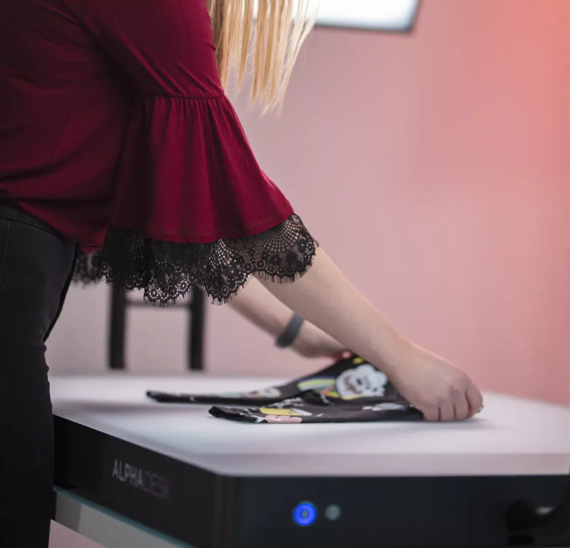 Femme pliant des vêtements d’enfant sur un bureau blanc avec Alphadesk